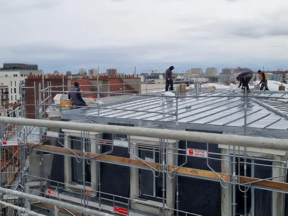 Scène extérieure sous la pluie montrant l'évacuation d'eau pluviale depuis une toiture en tuiles terre cuite vers une gouttière métallique