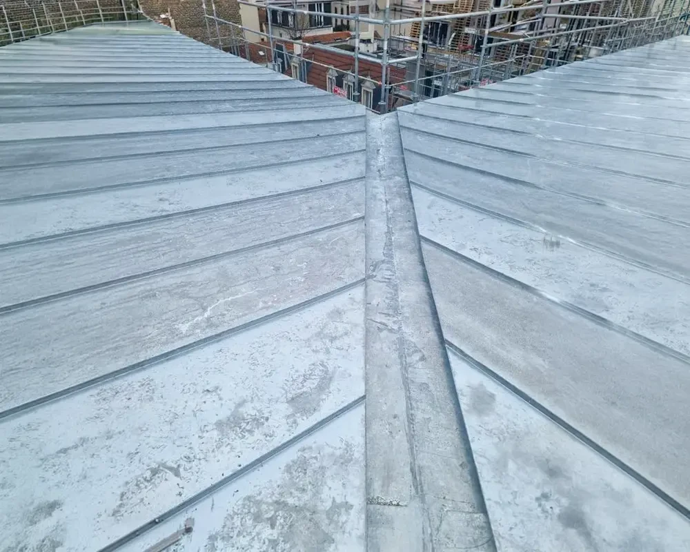 Goulet de toit clignotant en plomb, créant un joint étanche entre les tuiles de toit et la paroi de brique sur une maison domestique