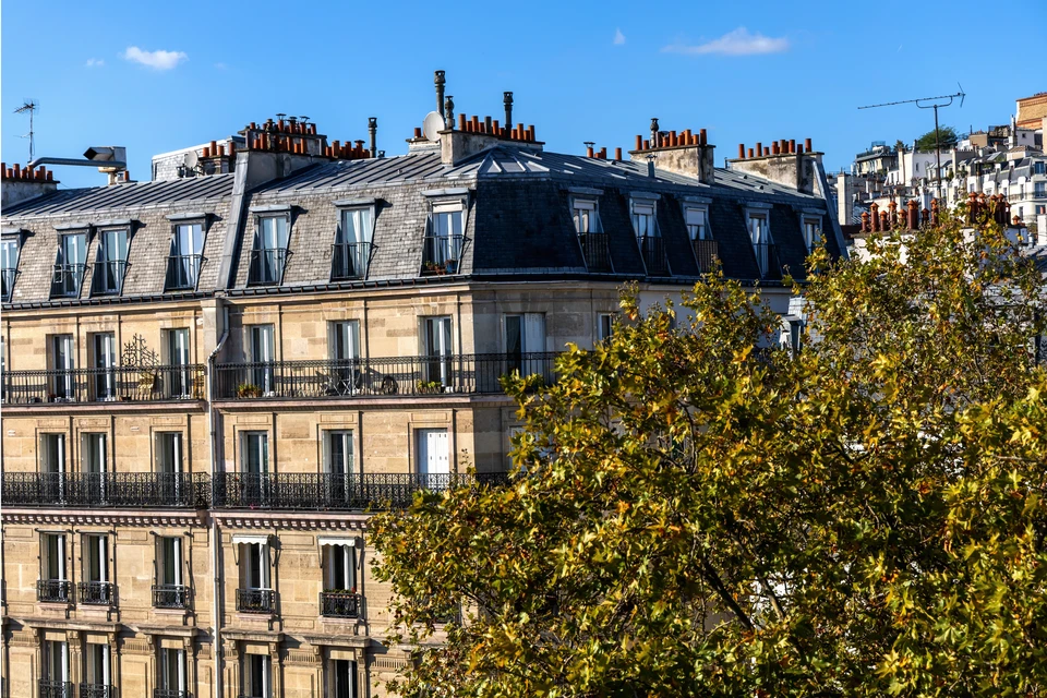 Toitures en tuiles terre cuite rouge-brun avec lucarnes à fenêtres blanches, murs crépi beige